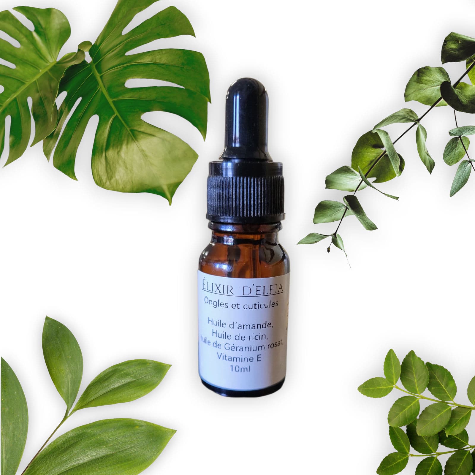 Amber glass dropper bottle of Elixir d'Elfia nail oil surrounded by various green leaves.